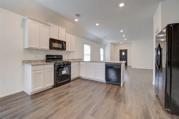 a large kitchen with a stove a sink dishwasher a refrigerator and a microwave oven on the wooden floor