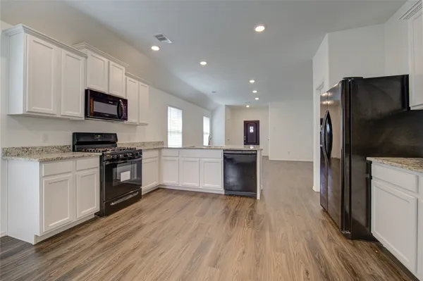 a kitchen with granite countertop a refrigerator oven a sink dishwasher and a stove with wooden floor