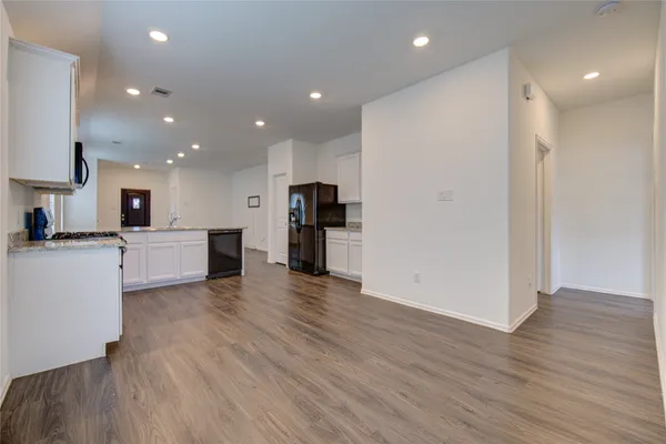 a view of a kitchen with refrigerator and wooden floor