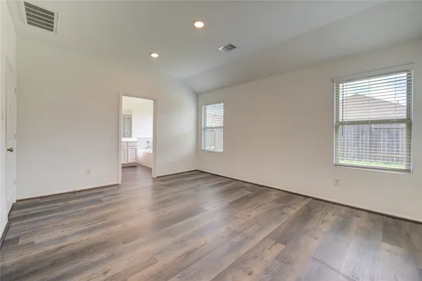 a view of an empty room with wooden floor and window
