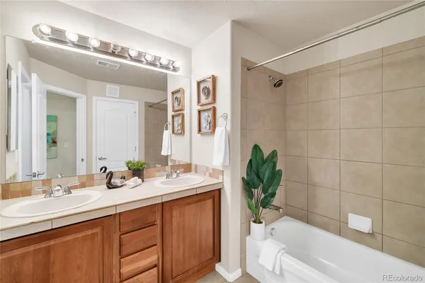 a bathroom with a granite countertop bathtub a sink and a mirror