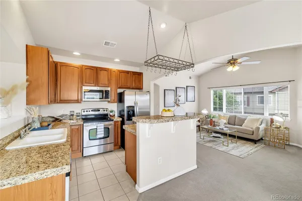 a kitchen with stainless steel appliances granite countertop a stove top oven a sink dishwasher a dining table and chairs with wooden floor