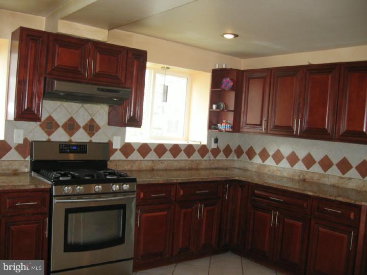 7007 Hilltop Road Upper Darby, PA 19082 - Photo 7 of 20 a kitchen with granite countertop stove top oven wooden cabinetry and granite counter