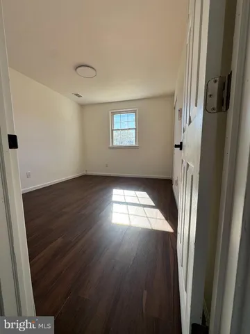 an empty room with wooden floor fireplace and windows