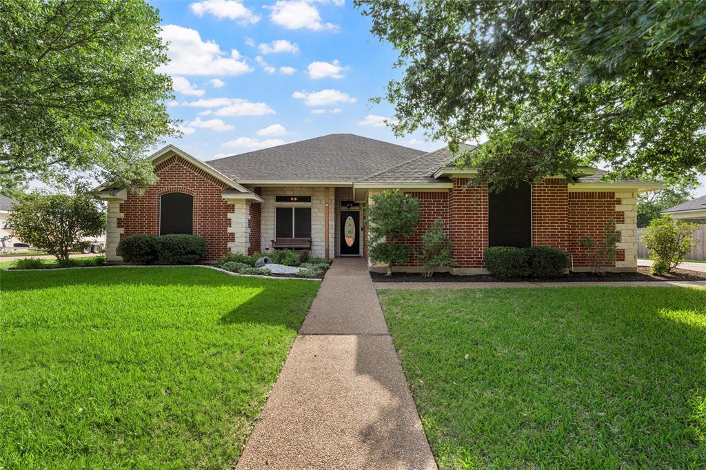 View of front of home with a front lawn, brick siding, and a shingled roof
