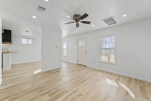 a view of an empty room with a window and wooden floor