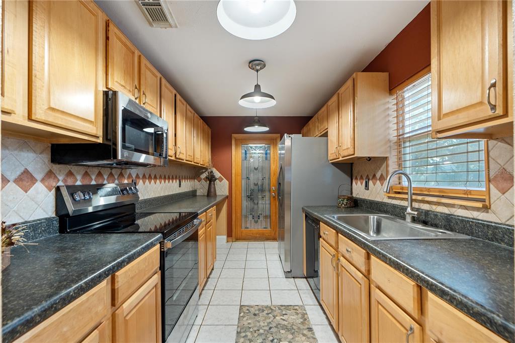 4008 Windswept Avenue Spring Hill, FL 34606 - Photo 8 of 32 a kitchen with stainless steel appliances granite countertop a sink a stove and a wooden cabinets