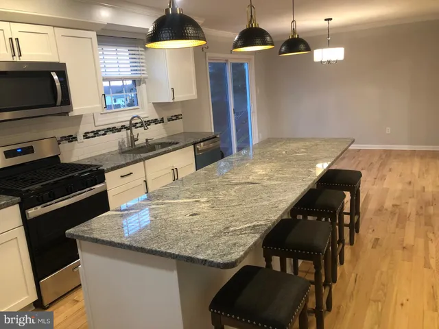 a kitchen with granite countertop kitchen island stainless steel appliances a sink stove and microwave