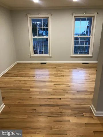 a view of empty room with window and wooden floor