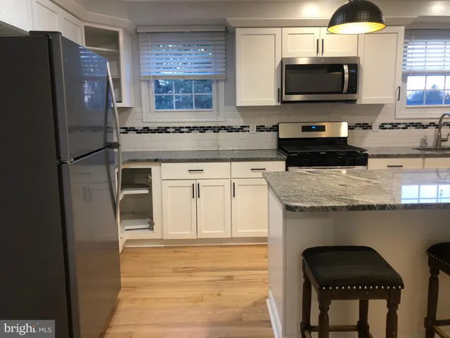 a kitchen with granite countertop a refrigerator stove and microwave