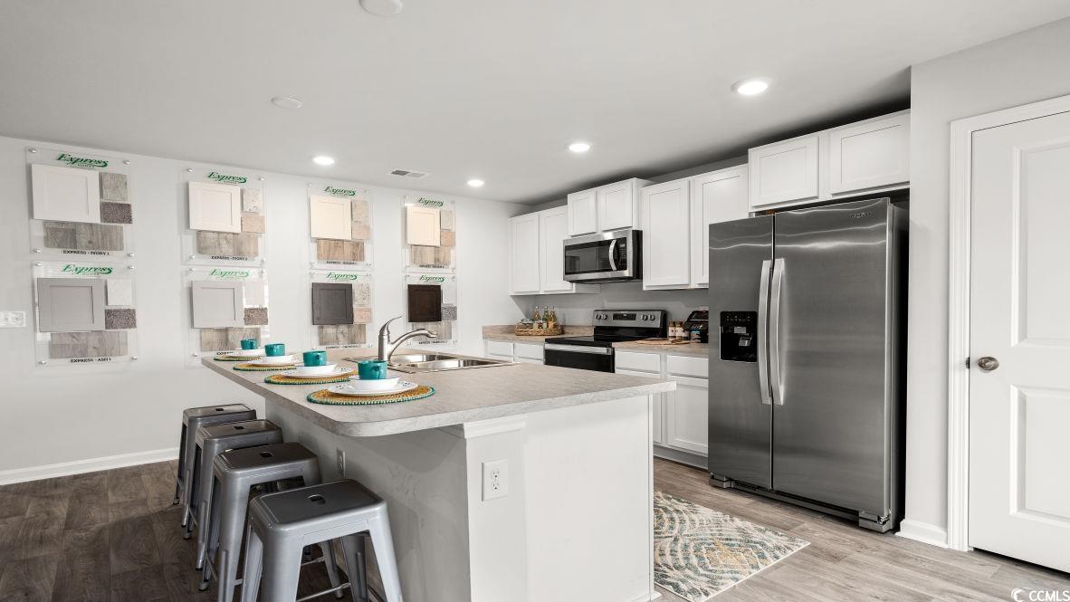 543 Acosta Circle Conway, SC 29527 - Photo 6 of 26 Kitchen featuring appliances with stainless steel finishes, white cabinetry, light countertops, a breakfast bar area, and a kitchen island with sink