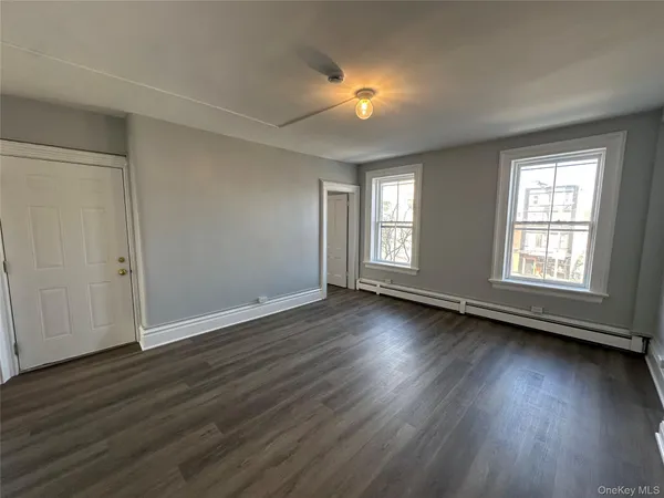 an empty room with wooden floor and windows with curtains view
