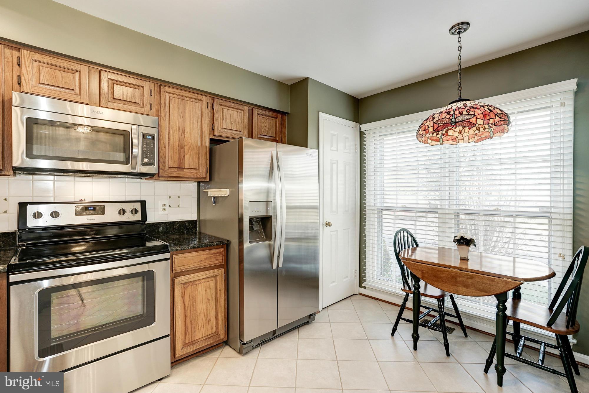 7415 Ridge Oak Court Springfield, VA 22153 - Photo 6 of 30 a kitchen with stainless steel appliances kitchen island granite countertop a table chairs and refrigerator