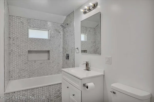 a bathroom with a sink a toilet a mirror and shower