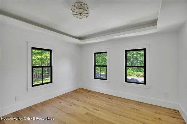 a view of an empty room with window and wooden floor