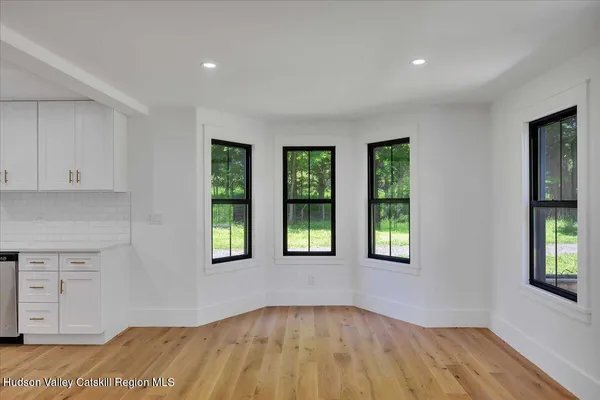 a view of an empty room with window and wooden floor