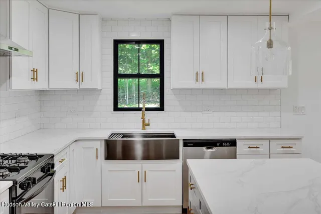 a kitchen with stainless steel appliances a stove a sink and white cabinets