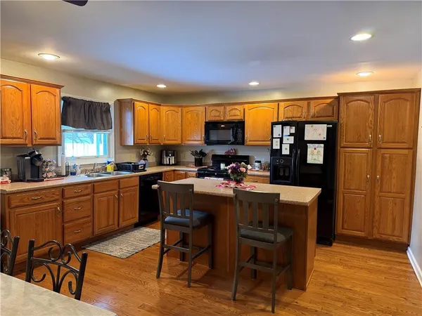 a kitchen with stainless steel appliances granite countertop a refrigerator a sink dishwasher a dining table and chairs with wooden floor