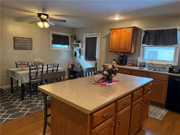 a kitchen with a stove a kitchen island a sink dishwasher a dining table and chairs with wooden cabinets