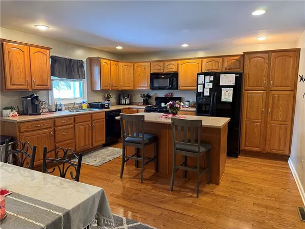 a kitchen with stainless steel appliances granite countertop a table chairs refrigerator and sink