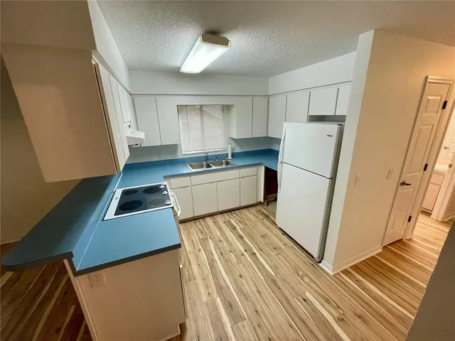 a kitchen with a refrigerator a stove and white cabinets