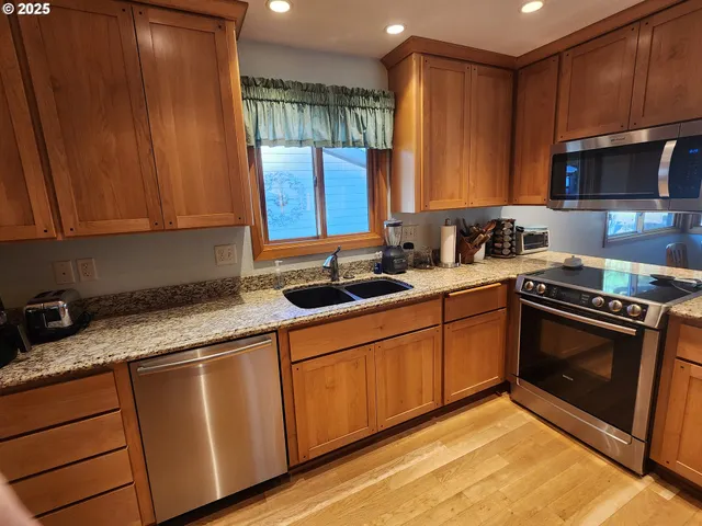 a view of kitchen with stainless steel appliances wooden floor