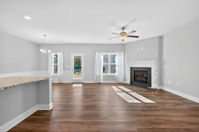 an empty room with windows fireplace and a kitchen view