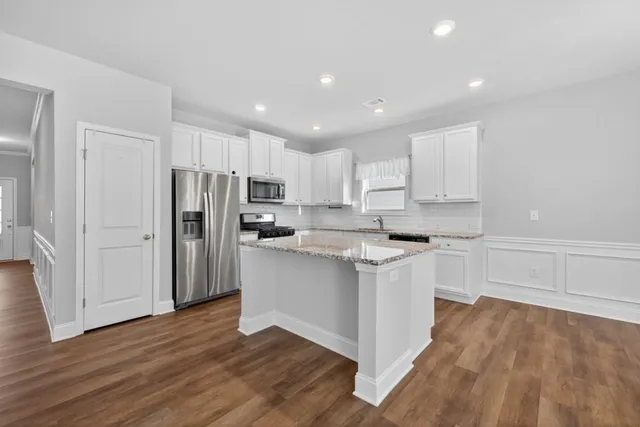 a kitchen with stainless steel appliances granite countertop a refrigerator sink and white cabinets