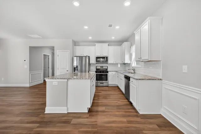 a large kitchen with stainless steel appliances granite countertop a stove a sink and a refrigerator