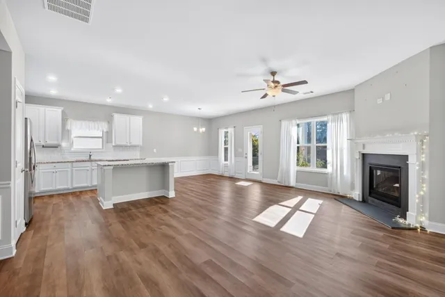 a view of an empty room and kitchen with fireplace wooden floor