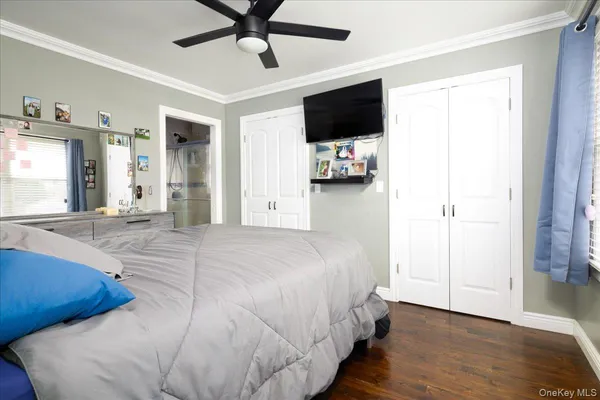 a bedroom with a bed and a flat tv screen on dresser