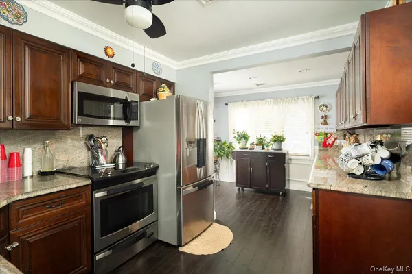 a kitchen with stainless steel appliances granite countertop a stove a sink dishwasher a refrigerator and a microwave oven with wooden floor