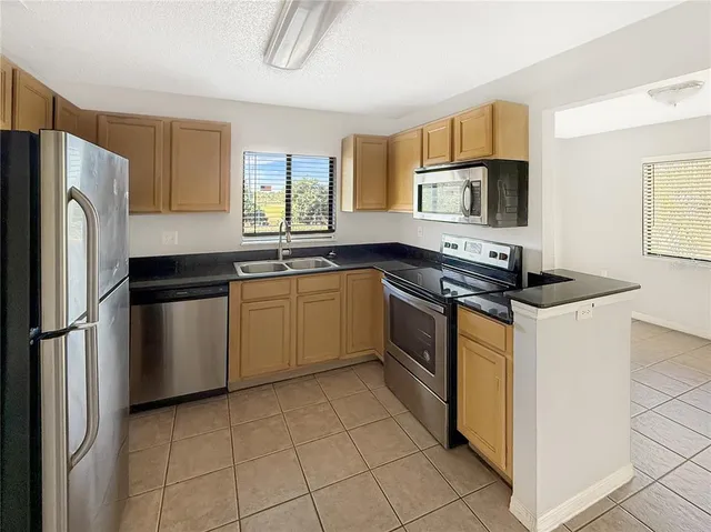 a kitchen with stainless steel appliances granite countertop a stove a sink dishwasher a refrigerator and a microwave