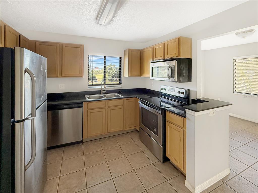 90 Hidden Lake Drive, Unit 132 Sanford, FL 32773 - Photo 5 of 13 a kitchen with stainless steel appliances granite countertop a stove a sink dishwasher a refrigerator and a microwave