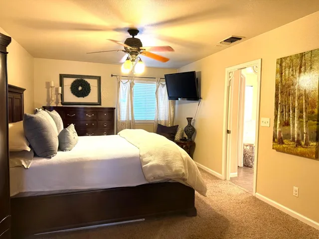 a bedroom with a bed a flat screen tv and a chandelier