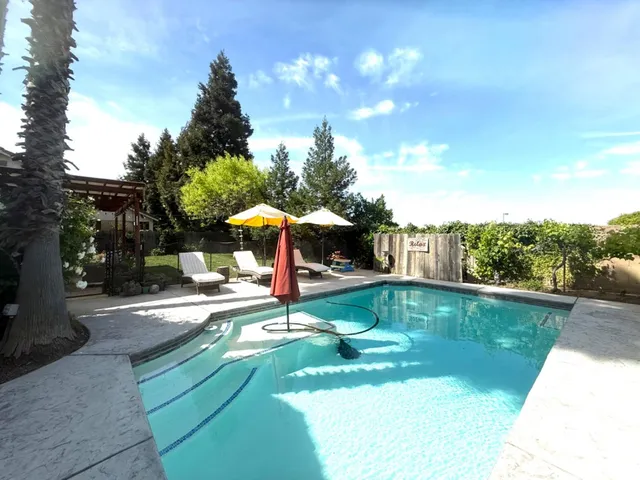a view of a swimming pool with a table and chairs under an umbrella