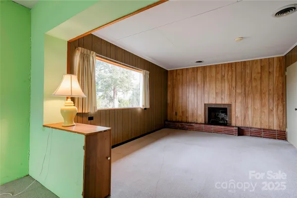 a view of an empty room with a window and fireplace