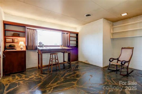 a view of a workspace with furniture and a window