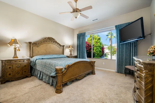 a bedroom with a large bed and a flat tv screen on dresser