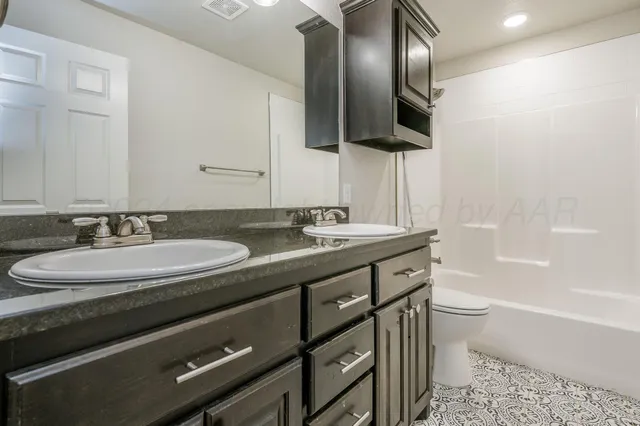 a bathroom with a granite countertop sink a large mirror a toilet and bathtub