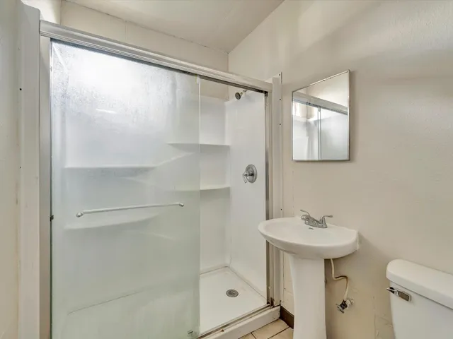 a bathroom with a shower sink vanity and mirror