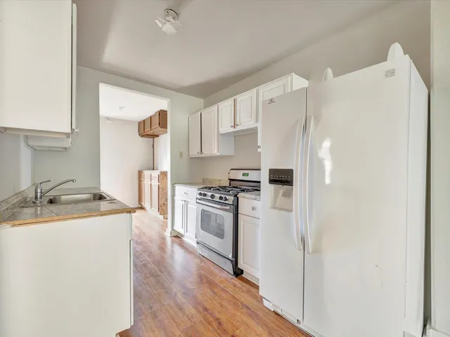 a kitchen with a refrigerator a stove top oven a sink and cabinets