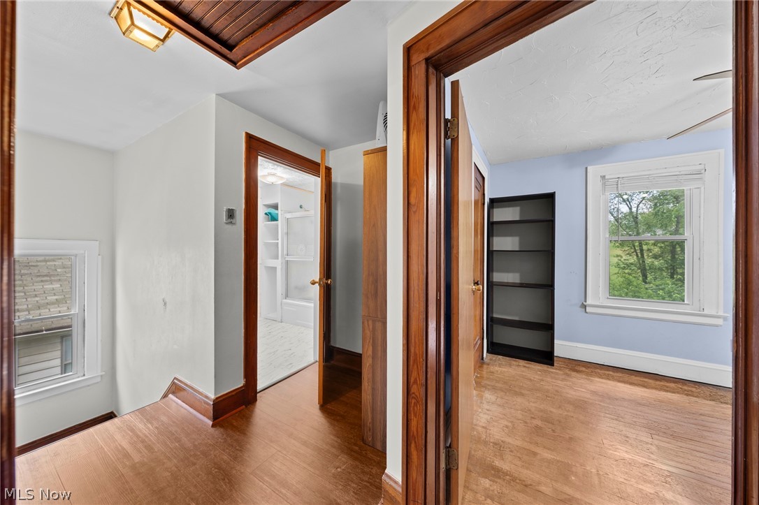 819 Keeney Street Akron, OH 44310 - Photo 17 of 24 Hallway featuring wood-finish flooring, a white ceiling with a flush-mount light fixture, and solid wood trim