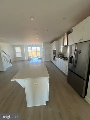 a large kitchen with stainless steel appliances a large counter top a stove and a refrigerator