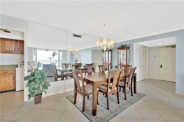 a view of a dining room and livingroom with furniture a rug a chandelier and kitchen view