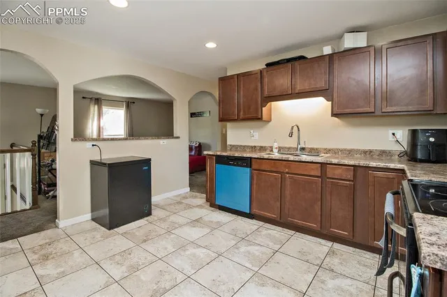 a kitchen with granite countertop a stove a sink and a refrigerator
