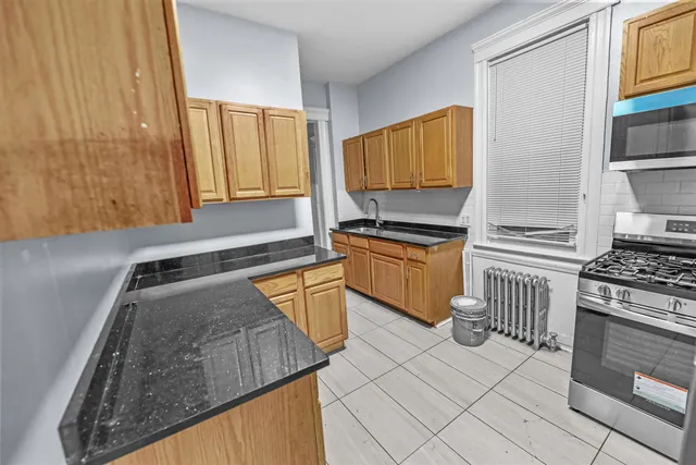 a kitchen with granite countertop a sink a stove and cabinets