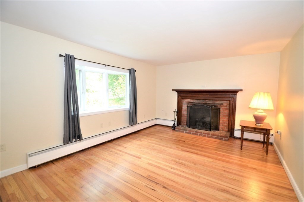 95 Pine Hill Road Ashland, MA 01721 - Photo 13 of 30 a view of an empty room with wooden floor a fireplace and a window