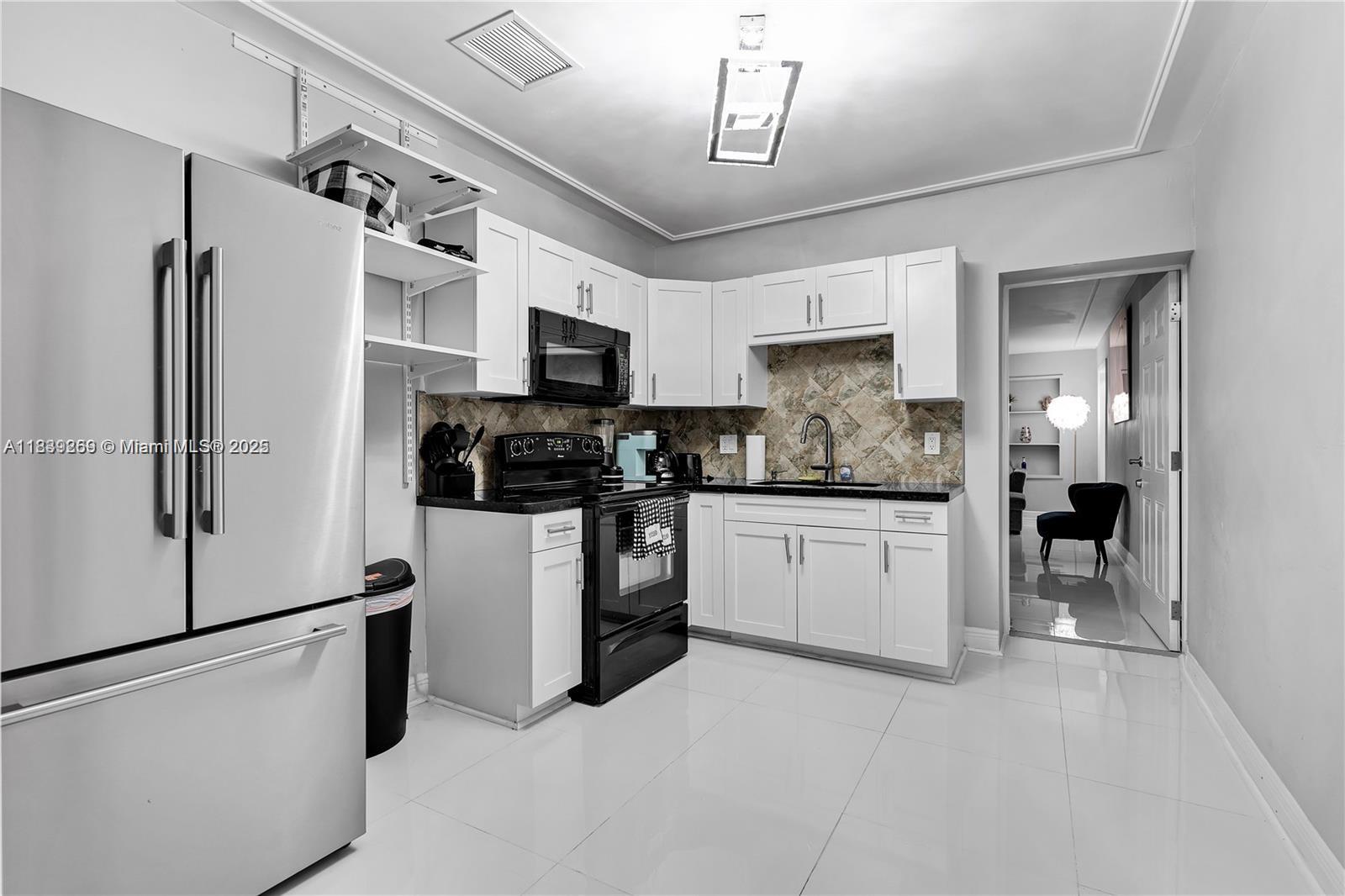 1761 Southwest 14th Street Miami, FL 33145 - Photo 13 of 37 a kitchen with stainless steel appliances granite countertop a refrigerator a stove a microwave oven a sink with island and chairs