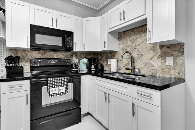 a kitchen with stainless steel appliances granite countertop white cabinets a stove a sink and dishwasher